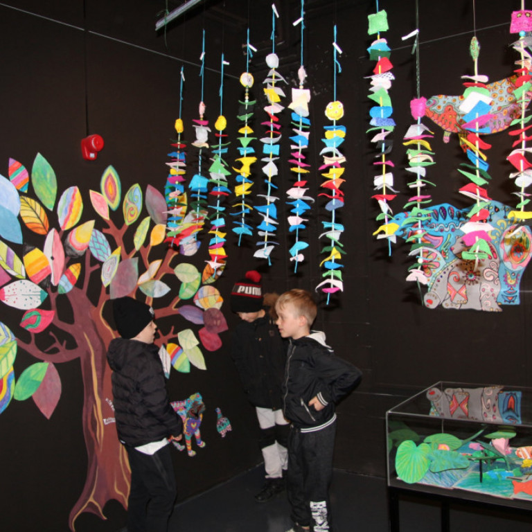 Svartklæddir áhorfendur innan um litskrúðug listaverk