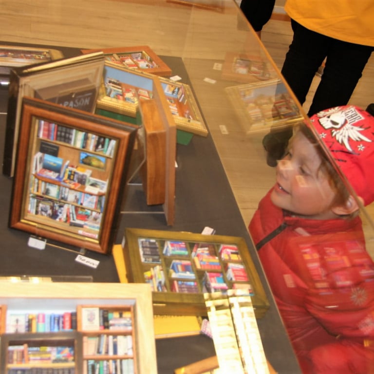 Ungur sýningargestur skoðar álfabækur GARASON í Átthagastofu Bókasafns Reykjanesbæjar